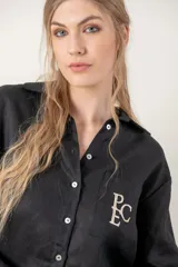 Camisa de lino color gris claro con bordado de monograma PEC en el bolsillo.