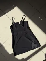 Vestido corto negro, ajustado al cuerpo, con escote pronunciado en V y tirantes finos ajustables. Presenta una abertura lateral en la falda.