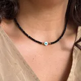 Collar corto de cristal checo negro de 4mm con dije de ojo turco en vidrio y bolitas de acero inoxidable dorado.