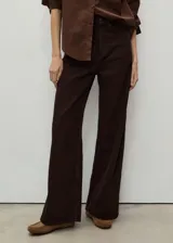 Pantalón de jean acampanado color marrón oscuro, con tiro alto, cinco bolsillos y cierre frontal con cremallera y botón.