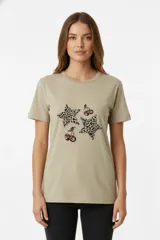 Remera color beige de algodón con cuello redondo y manga corta. Estampado con dos estrellas con patrón animal print y dos cerezas.