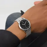 Reloj Guess modelo Chandler con caja de 40mm y pulsera de malla milanesa de acero inoxidable plateado. La esfera es negra con marcadores de hora plateados y un pequeño cristal como índice a las 12. Presenta agujas plateadas y corona lateral.