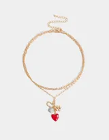 Collar dorado de tres hilos con dijes colgantes: corazón rojo con strass, trébol dorado, herradura dorada con logo de la marca y vaquita de San Antonio celeste con lunares blancos.
