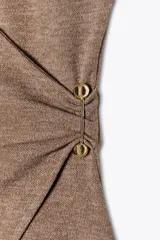 Top marrón de escote pico cruzado y manga sisa caída. Tejido con textura y broche metálico lateral. Bajo asimétrico.
