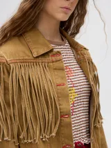 Campera de jean marrón claro con flecos en el pecho y mangas.