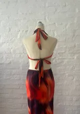 Vestido largo con estampado abstracto en tonos naranja y azul, con escote halter, espalda descubierta y aberturas laterales en la cintura.