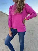 Polerón de punto color fucsia, con detalles en naranja en el bajo y diseño holgado.