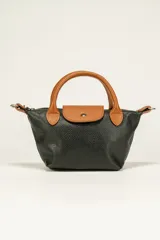 Cartera mini de cuero color negro con detalles en marrón, con correa corta y cierre con broche.
