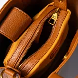 Cartera mediana color habano, de símil cuero, con doble asa corta y correa larga regulable y desmontable. Tiene acceso abierto, dos compartimentos y un bolsillo interno con cierre.