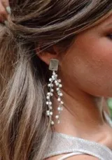 Aros colgantes plateados con base cuadrada y múltiples cadenas finas con pequeñas perlas blancas.