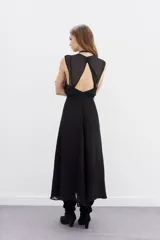 Vestido largo negro de viscosa georgette, con caída fluida y lazo trenzado en la cintura. Presenta doble capa en la parte superior que combina recortes y transparencias.
