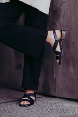 Sandalias bajas color beige con tiras cruzadas y elástico dorado en el talón.