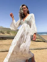 Vestido largo color crudo con estampado dorado, escote en V y mangas acampanadas.