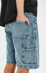 Bermuda de denim celeste con calce oversize, estilo carpintero y proceso de efecto desgaste.