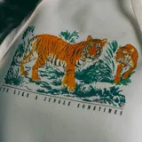 Canguro blanco con estampado de tigres y vegetación selvática.
