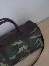 Bolso de lona color negro con detalles en cuero color tostado. Tiene doble asa de mano y correa de hombro ajustable y extraíble.