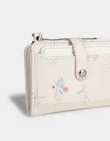Billetera pequeña de cuerina color crema con estampado de flores y lazos. Tiene cierre superior y broche con botón para cerrar.