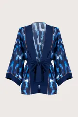 Kimono corto azul con estampado abstracto en tonos azules y blancos, con detalles dorados. Presenta mangas 3/4 amplias, cinturón liso y guarda frontal en color azul liso.