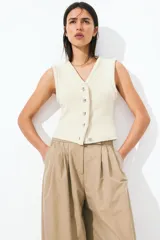 Pantalón color beige de corte holgado con silueta baggy. Modelo de tiro alto con pinzas, elástico revestido en la cintura, cierre y pretina prolongada con botón y corchete ocultos. Bolsillos al bies y bolsillos decorativos atrás.
