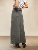 Falda larga de jean color gris oscuro, con corte en A y costuras verticales decorativas en el frente. Tiene bolsillos laterales y cierre con botón y cremallera.