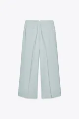 Pantalón de tiro medio color celeste confeccionado en hilatura con mezcla de lyocell. Tiene bolsillos laterales, pinzas delanteras, pierna ancha y cierre frontal con cremallera y botón.