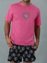 Conjunto de pijama Calvin Klein de dos piezas. Incluye una remera rosa de manga corta con cuello redondo y logo estampado en el pecho, y un short negro con estampado de corazones y logo de la marca.