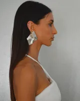 Aros colgantes plateados con forma geométrica irregular y diseño texturizado.