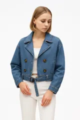 Chaqueta corta de jean azul con doble botonadura, cuello solapa, cinturón con hebilla y puños con botón.