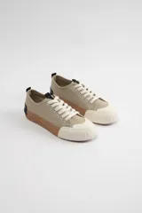 Zapatillas acordonadas color beige con suela marrón y puntera blanca.