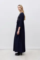 Vestido largo azul marino con bordados dorados en el frente, mangas largas y falda acampanada.