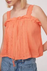Musculosa color salmón con breteles finos y detalle de puntilla en el escote.
