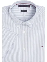 Camisa de manga corta Tommy Hilfiger Heritage, de corte regular, confeccionada en tela Oxford a rayas verticales celestes y blancas. Tiene cuello abotonado, cierre con botones y logo de Tommy Hilfiger bordado en el pecho.