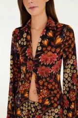 Camisa negra con estampado floral en tonos naranja, rojo y amarillo. Corte recto y fluido con cierre frontal con botones. Cuello clásico y manga larga.