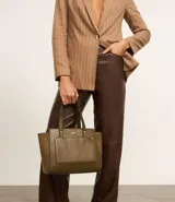 Cartera mediana color beige con paneles laterales de gamuza, doble asa de mano y correa larga desmontable.