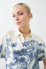 Camisa de manga corta con estampado paisley en tonos azul y blanco, con cuello clásico y cierre con botones.