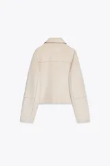 Cazadora color crema de cuello solapa y manga larga. Bolsillos delanteros de plastrón con solapa. Cierre frontal con botones.