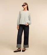 Blusa celeste de crepé con textura plisada, cuello redondo, mangas largas abullonadas y puños ajustados.