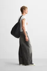 Pantalón de jean negro de corte amplio, con cinco bolsillos, efecto lavado y cierre frontal con cremallera y botón.