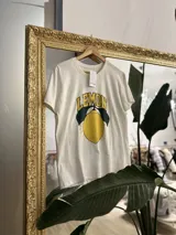 Remerón blanco de algodón con estampa de un limón con hojas y la palabra "LEMON" en amarillo y negro.