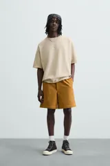 Camiseta color beige de punto tejido en hilatura de algodón, corte relaxed fit, cuello redondo y manga corta. Estampación con efecto lavado combinada a contraste en espalda. Acabados irregulares.