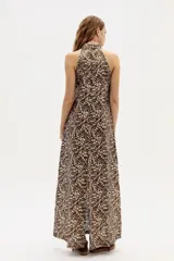 Vestido largo con estampado abstracto en tonos marrones y beige, cuello halter y corte en línea A. Confeccionado en lino 100% natural con terminación metalizada.