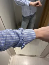 Camisa celeste a rayas blancas, de algodón y lino, con cuello mao y volados en cuello y mangas. Cierre frontal con botones blancos.