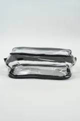 Neceser transparente con bordes negros y cierre dorado.