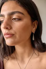 Aros colgantes de acero quirúrgico hipoalergénico con dije de piedra natural en forma de gota color azul oscuro.