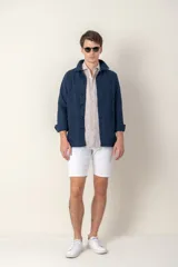 Sobre camisa azul marino de lino con cuello camisero, cierre frontal con botones, mangas largas con puños abotonados y bolsillos de parche en el pecho.