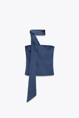 Top azul de satén con escote recto y hombros descubiertos. Tiene detalle de bufanda en el cuello y cierre lateral con cremallera oculta.