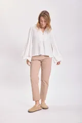Blusa blanca de mangas largas abullonadas con cuello en V y detalle de botón en el frente.