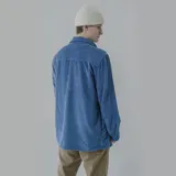 Camisa celeste de pana con corte oversize, cuello clásico, cierre frontal con botones, dos bolsillos con solapa en el pecho y mangas largas con puños abotonados.