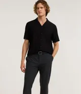 Pantalón de sastrería color gris claro, de corte recto y tobillero, con cintura elástica y cierre frontal.