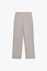 Pantalón de vestir color beige, de tiro alto, corte recto y bolsillos laterales.